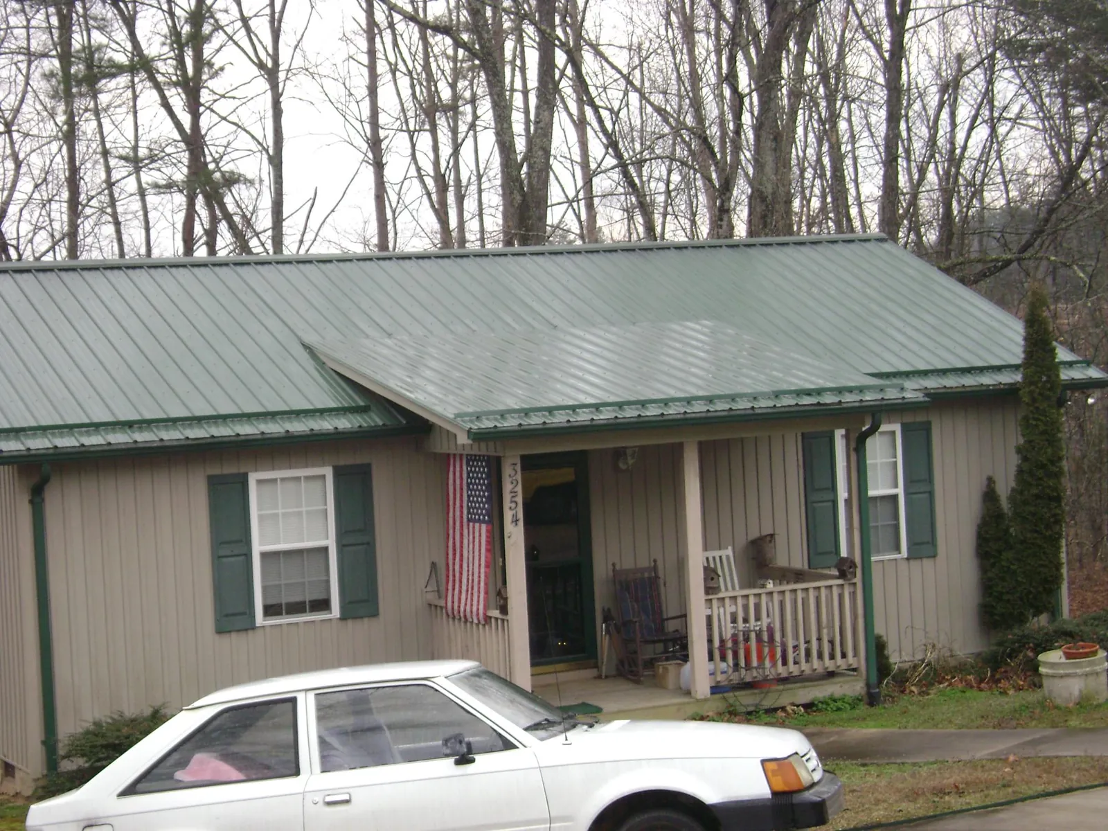 Green metal roof and front porch on a tan sided cottage in Dayton